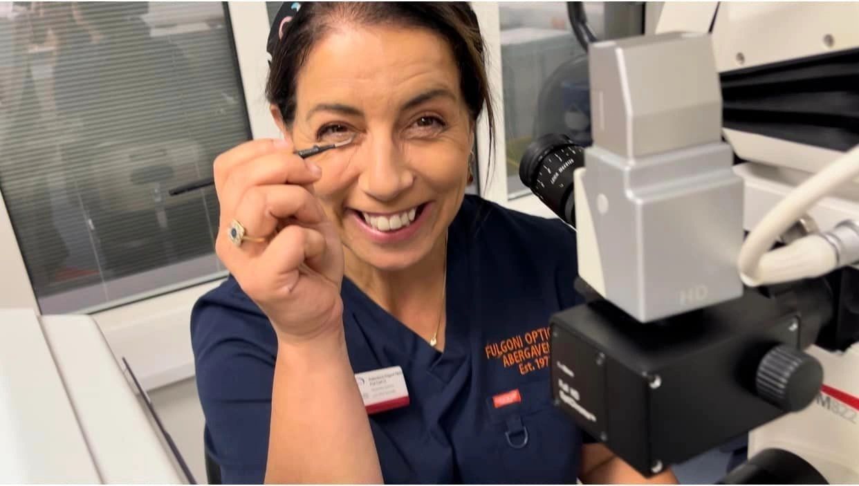 Francesca Fulgoni at the slit-lamp microscope in her Fulgoni-branded surgical scrubs at 17 Cross Street, Abergavenny